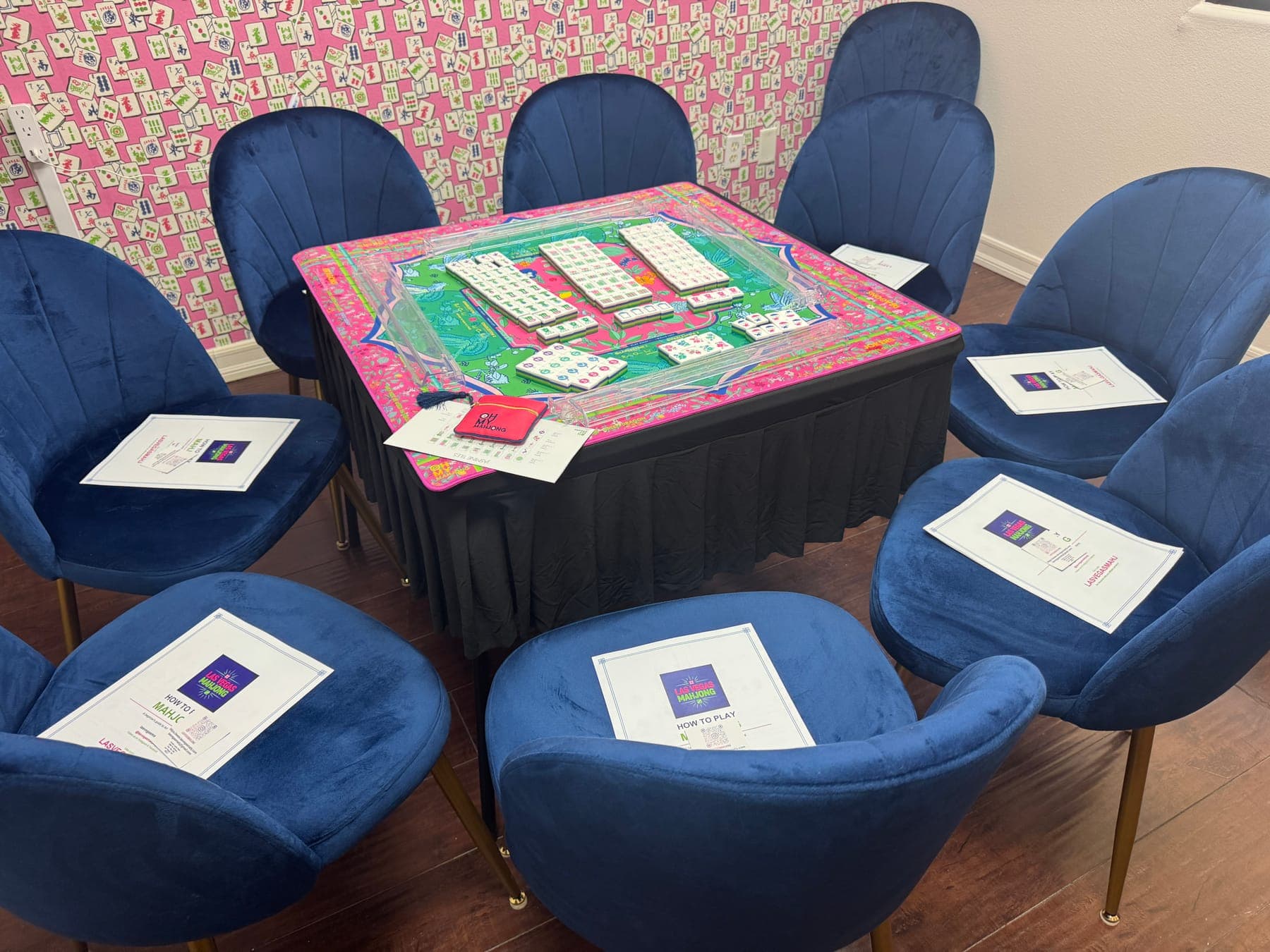 A mahjong lesson table at the Las Vegas Mahjong Studio set with tiles, racks, a mat and printed how-to-play materials on every chair