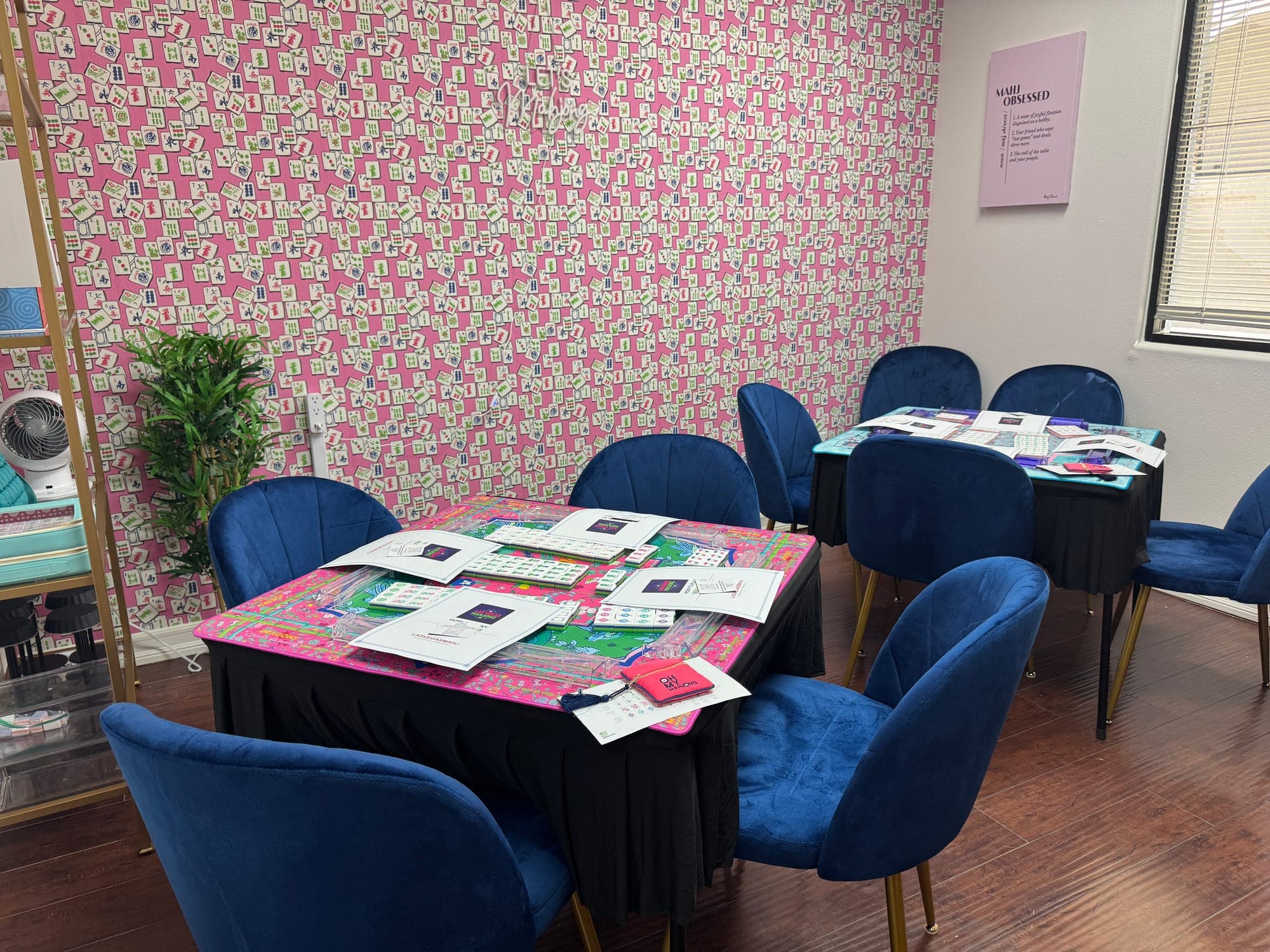 The Lucky Wishbone lesson room at the Las Vegas Mahjong Studio, with mahjong tables, blue velvet chairs and a pink tile-patterned wall