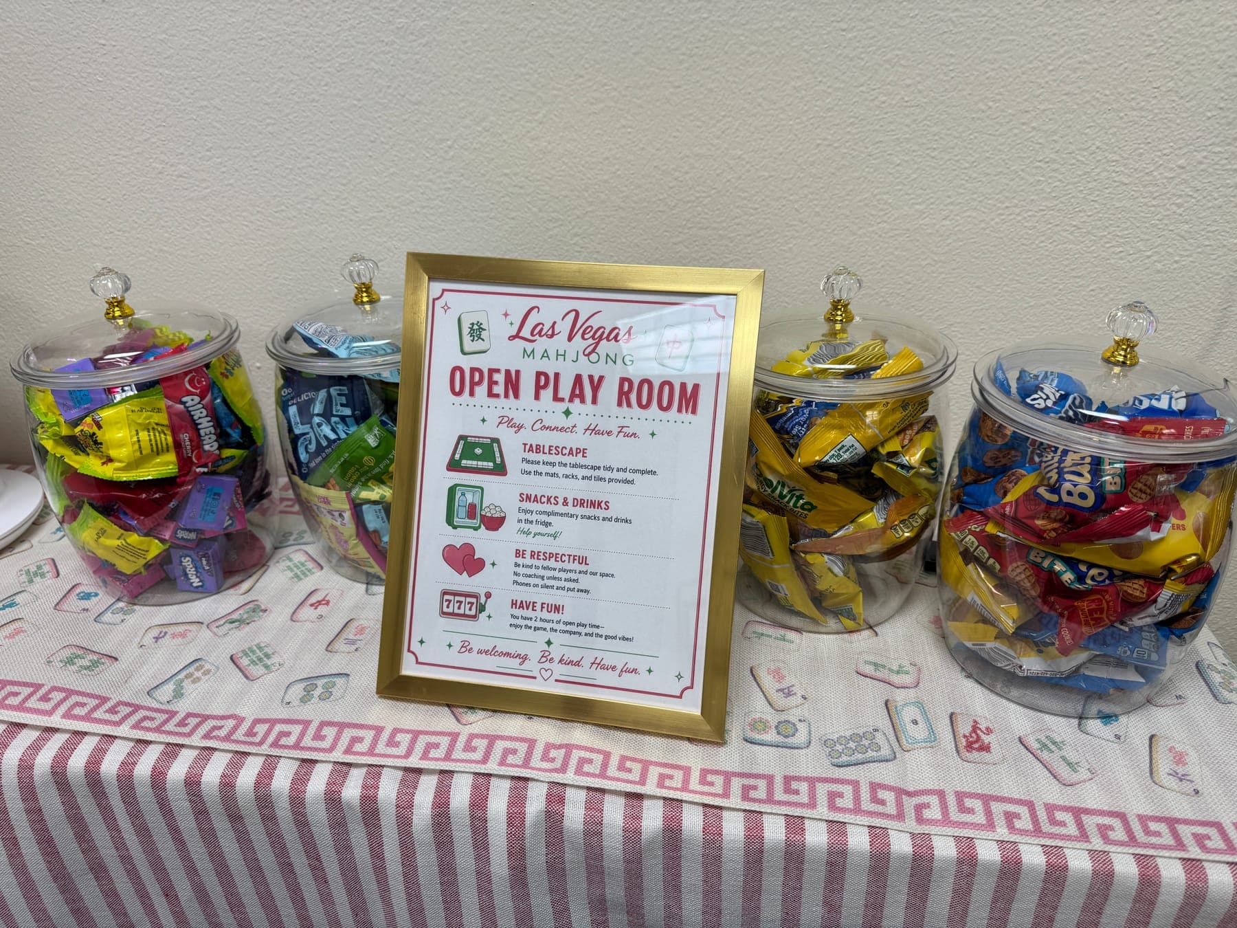 The snack station in the open play room at the Las Vegas Mahjong Studio, beside a framed Open Play Room house rules sign